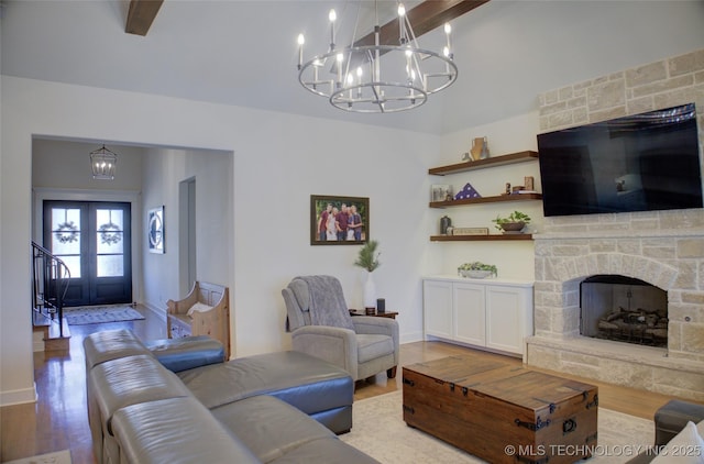 living room featuring an inviting chandelier, beam ceiling, light hardwood / wood-style floors, and french doors