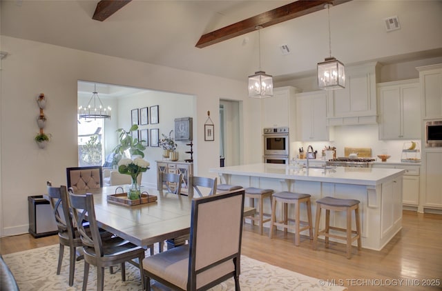 dining room featuring lofted ceiling with beams, a chandelier, sink, and light hardwood / wood-style flooring