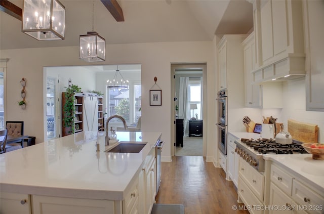 kitchen with decorative light fixtures, sink, vaulted ceiling with beams, a notable chandelier, and a center island with sink