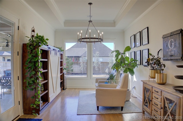 sitting room with a raised ceiling, crown molding, an inviting chandelier, and light hardwood / wood-style floors