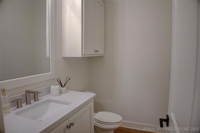 bathroom featuring toilet, vanity, and baseboards