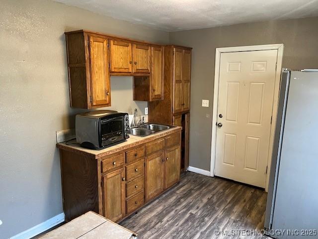 kitchen with stainless steel refrigerator, dark hardwood / wood-style flooring, and sink