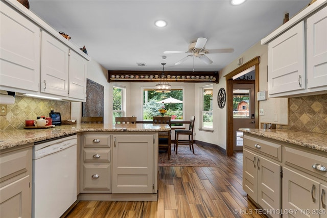 kitchen with light stone countertops, white cabinets, white dishwasher, and decorative light fixtures