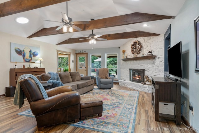 living room with a stone fireplace, vaulted ceiling with beams, and light hardwood / wood-style flooring