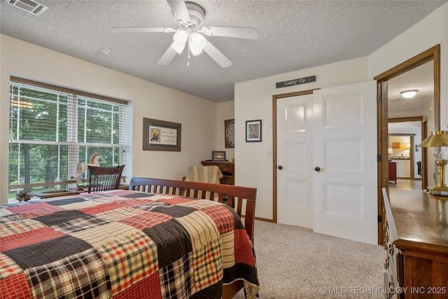 carpeted bedroom featuring ceiling fan and a textured ceiling