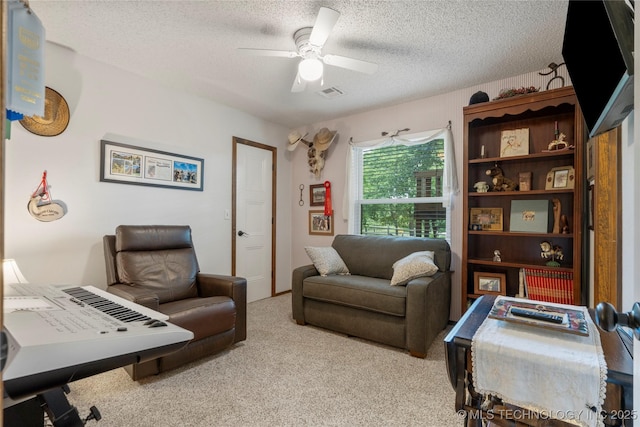 carpeted office space with a textured ceiling and ceiling fan