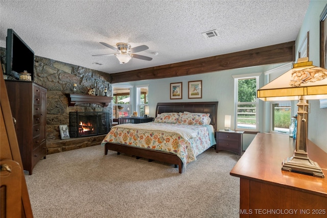 carpeted bedroom featuring ceiling fan, a stone fireplace, and a textured ceiling