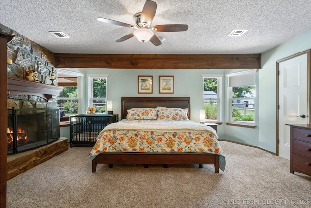 carpeted bedroom with multiple windows, ceiling fan, a textured ceiling, and a fireplace