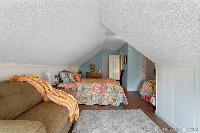 bedroom featuring dark wood-type flooring, a textured ceiling, and vaulted ceiling