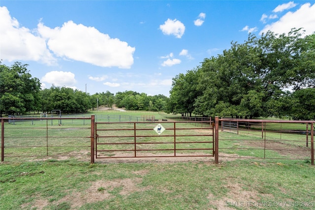 view of gate with a rural view and a lawn