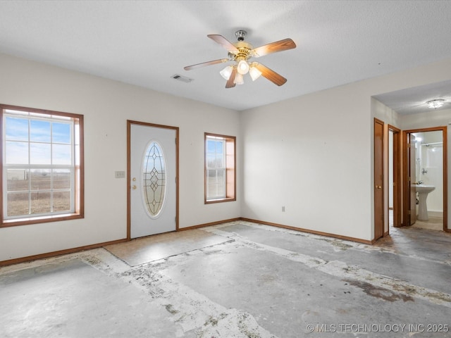 foyer featuring concrete flooring, a healthy amount of sunlight, and ceiling fan