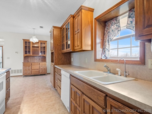 kitchen with sink, a textured ceiling, pendant lighting, white appliances, and backsplash