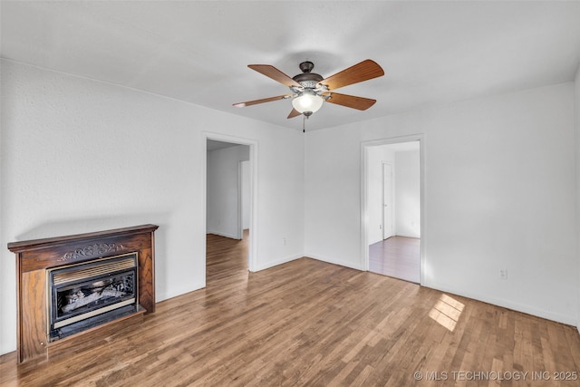 unfurnished living room featuring wood-type flooring, ceiling fan, and a fireplace