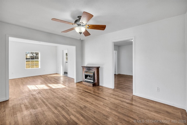 unfurnished living room with ceiling fan, hardwood / wood-style floors, and a fireplace