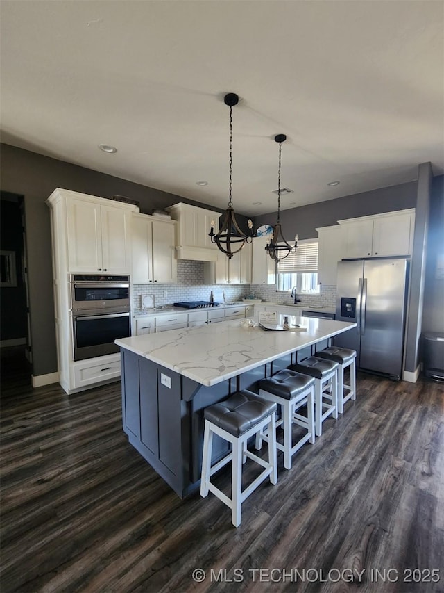 kitchen with white cabinetry, decorative light fixtures, stainless steel appliances, and a center island