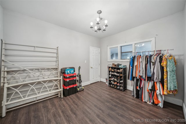 walk in closet featuring an inviting chandelier and dark hardwood / wood-style floors