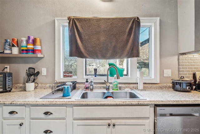 kitchen featuring white cabinetry, dishwasher, sink, and light stone counters