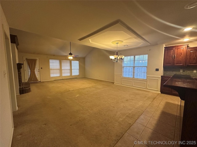 interior space featuring lofted ceiling, ceiling fan with notable chandelier, and light colored carpet