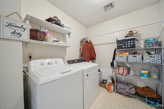 clothes washing area with washing machine and dryer and a textured ceiling