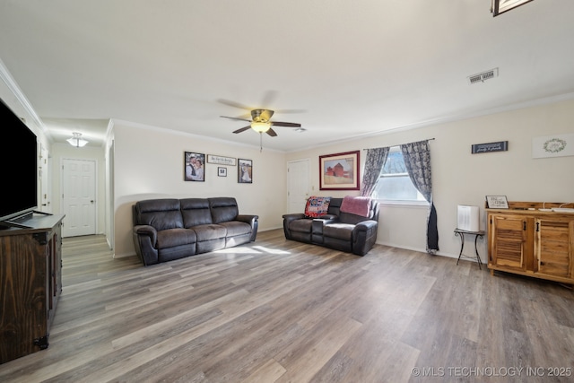 living room featuring ornamental molding, ceiling fan, and light wood-type flooring