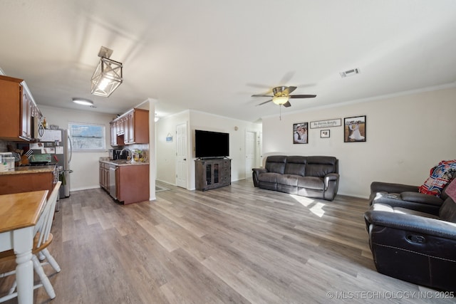 living room with sink, crown molding, light hardwood / wood-style flooring, and ceiling fan