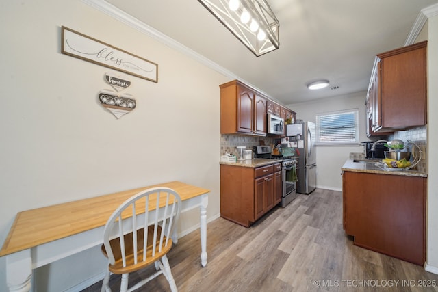 kitchen featuring sink, ornamental molding, stainless steel appliances, and light wood-type flooring