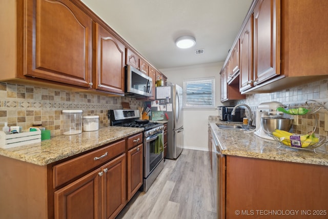 kitchen with light stone counters, appliances with stainless steel finishes, sink, and tasteful backsplash