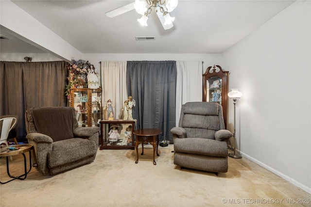 living area featuring a textured ceiling, carpet floors, and ceiling fan