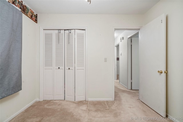 unfurnished bedroom featuring light carpet and a closet