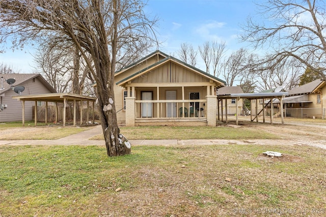 rear view of property with a carport, a porch, and a yard