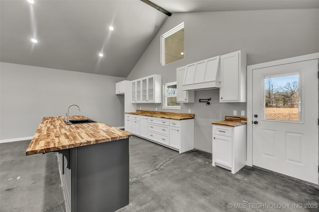 kitchen with white cabinetry, butcher block counters, sink, and a kitchen island with sink