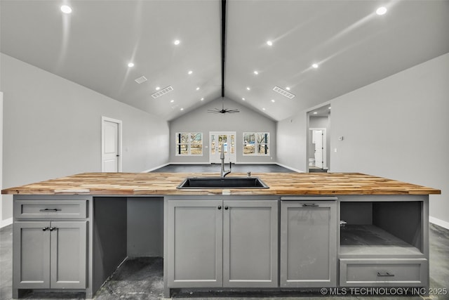 kitchen with gray cabinetry, butcher block countertops, vaulted ceiling, and sink