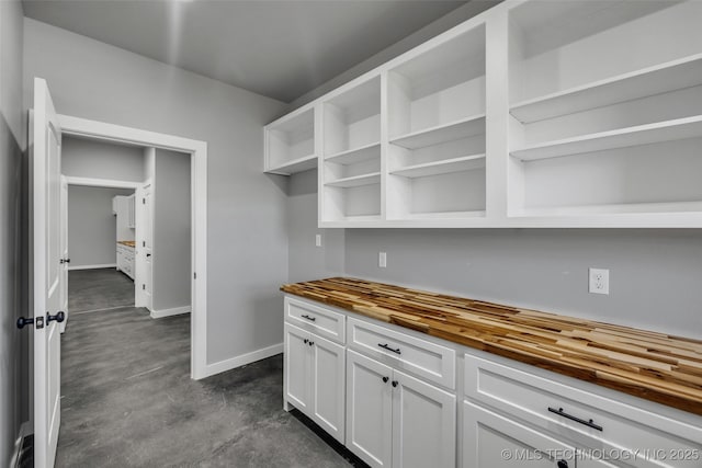 kitchen featuring butcher block countertops and white cabinets