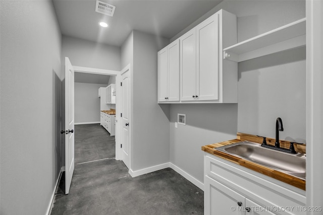 clothes washing area with sink, hookup for a washing machine, and cabinets