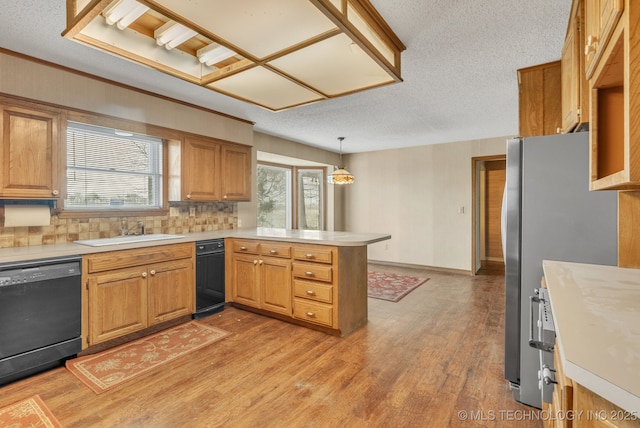 kitchen featuring pendant lighting, dishwasher, sink, kitchen peninsula, and light hardwood / wood-style flooring