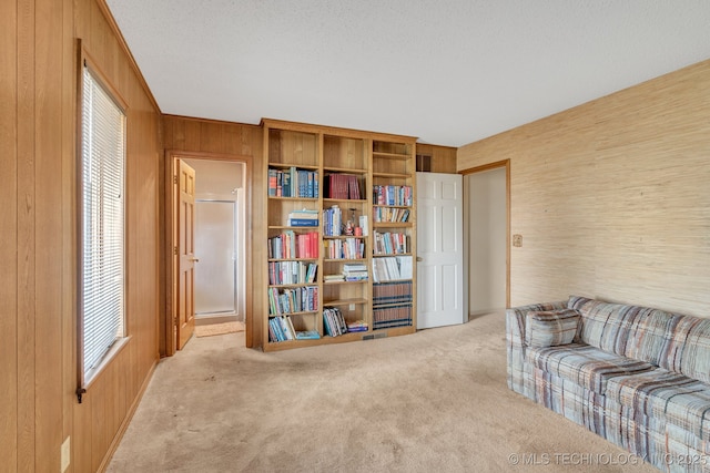 living area with wooden walls, light carpet, and a textured ceiling