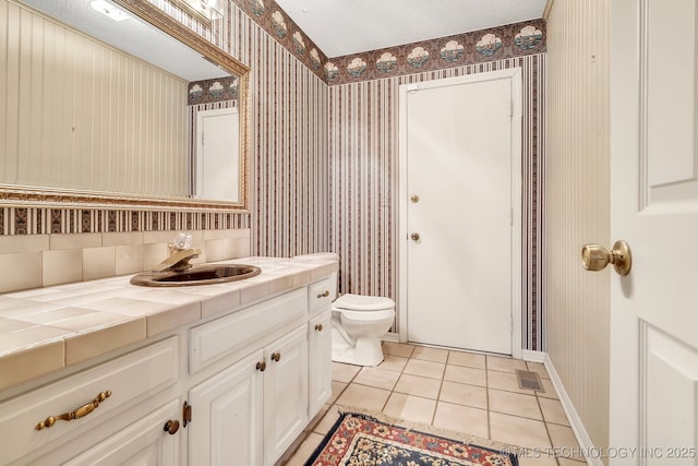 bathroom featuring vanity, a textured ceiling, tile patterned floors, and toilet