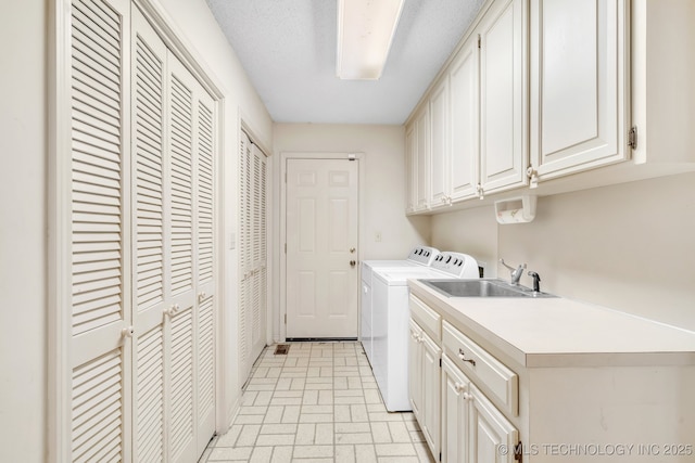 clothes washing area featuring cabinets, sink, and washer and dryer