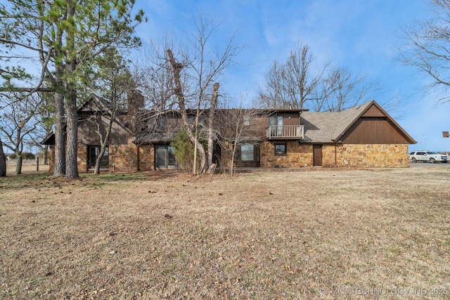 view of front of home with a balcony and a front lawn