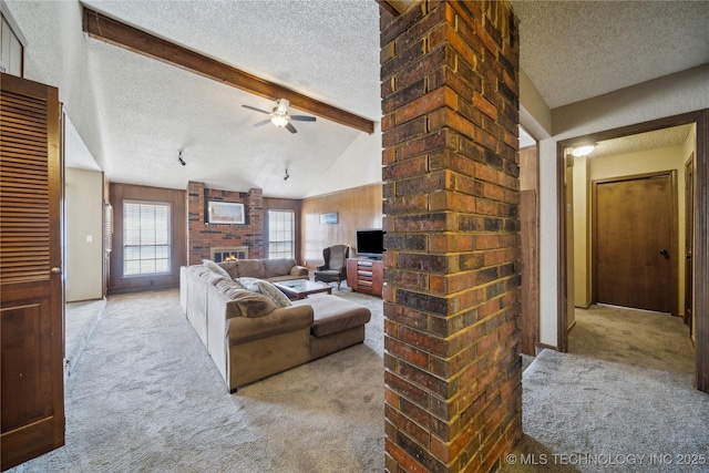 carpeted living room featuring ceiling fan, a fireplace, lofted ceiling with beams, and a textured ceiling