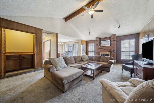 carpeted living room with sink, vaulted ceiling with beams, wooden walls, a textured ceiling, and ceiling fan with notable chandelier