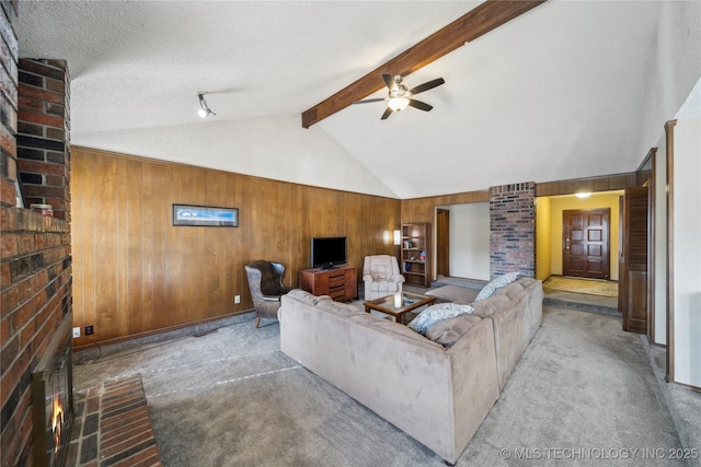 carpeted living room featuring a fireplace, wood walls, beam ceiling, ceiling fan, and a textured ceiling