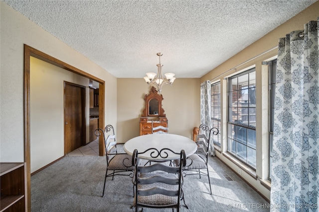 carpeted dining room featuring a chandelier and a textured ceiling