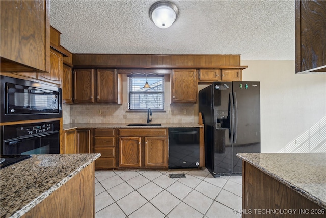 kitchen featuring light tile patterned floors, light stone countertops, sink, and black appliances