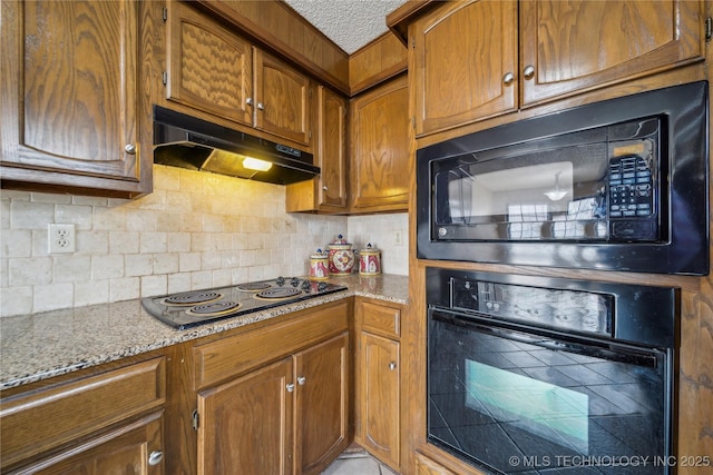 kitchen with tasteful backsplash, light stone countertops, a textured ceiling, and black appliances