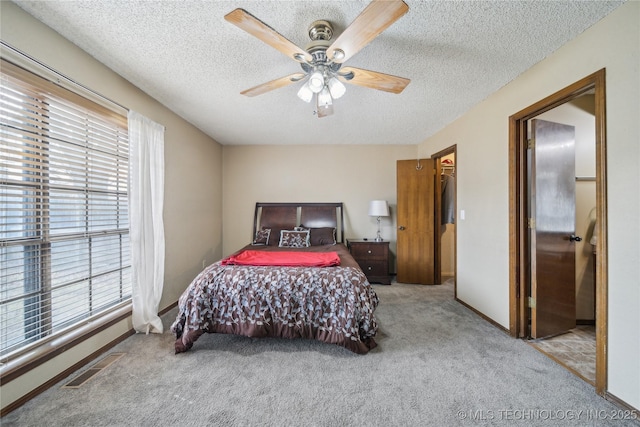 carpeted bedroom featuring ceiling fan, a spacious closet, and a textured ceiling