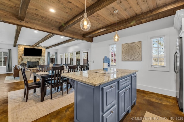 kitchen featuring light stone counters, decorative light fixtures, plenty of natural light, a kitchen island, and a fireplace