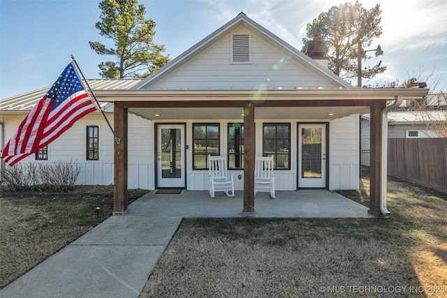 back of property with a lawn and covered porch