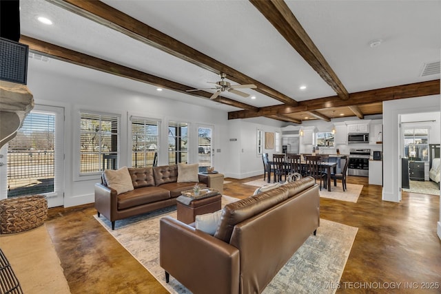 living room featuring plenty of natural light, concrete flooring, beamed ceiling, and ceiling fan