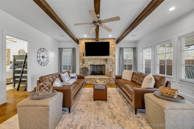 living room with ceiling fan, a fireplace, light hardwood / wood-style floors, and beamed ceiling